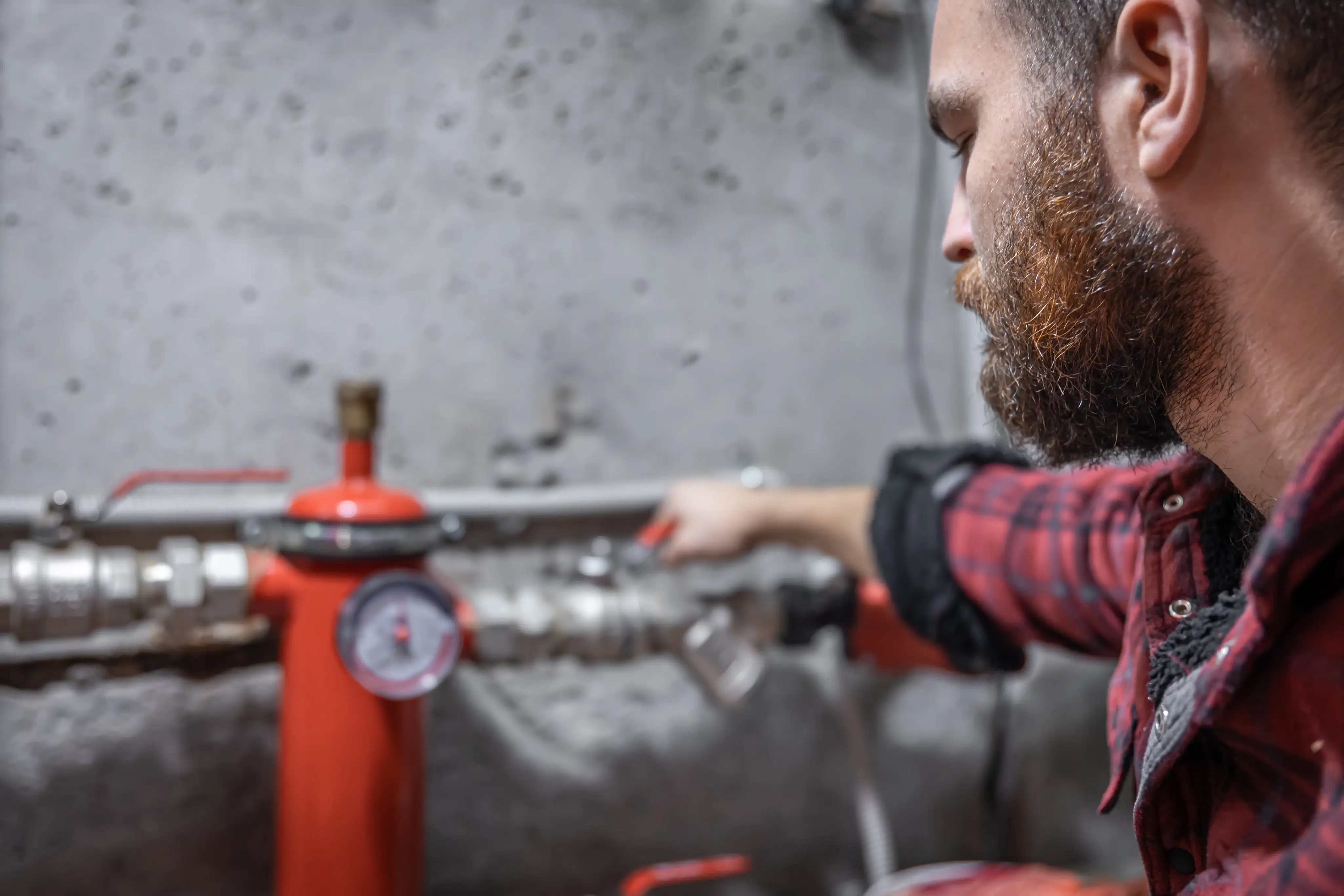 Plumber using pressure gauge and valve inspection to locate hidden water leaks