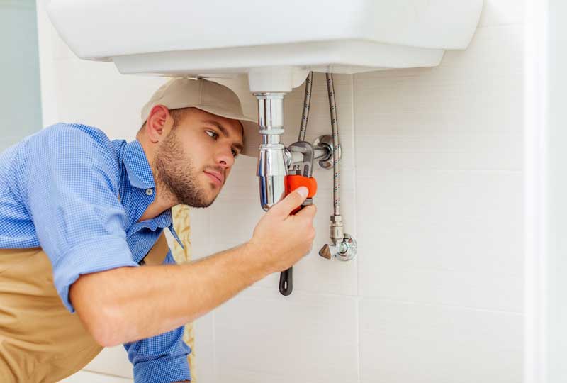 Licensed plumber repairing leaking tap and checking pipe fittings in Brisbane