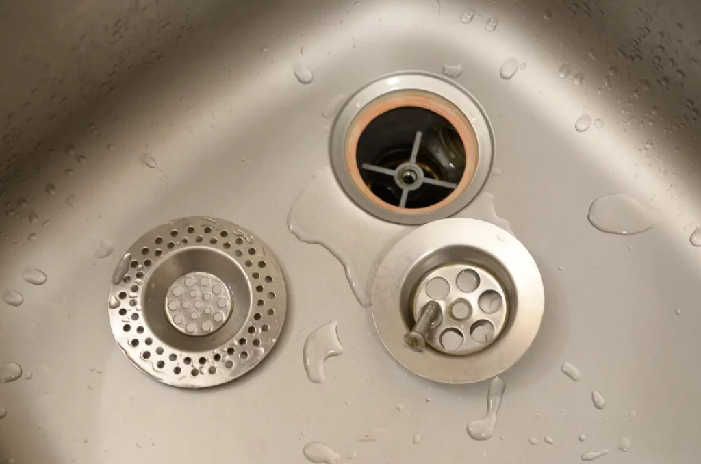 Open kitchen sink drain with removed cover, possible site for what causes blocked drain and how to fix blocked drain