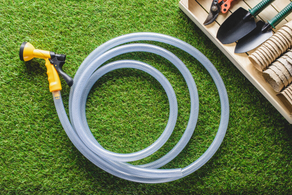 A top view of a hosepipe and gardening equipment, depicting outdoor items to check when learning how to detect a water leak around the garden.