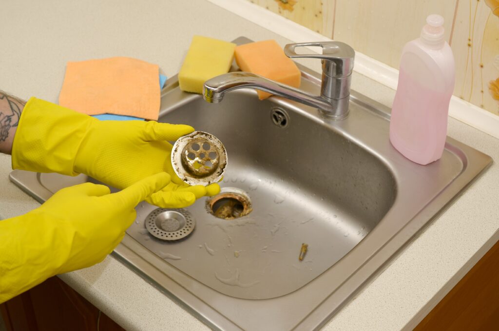 Blocked sink with visible debris, showing what affects drain cleaning cost for simple clogs. 