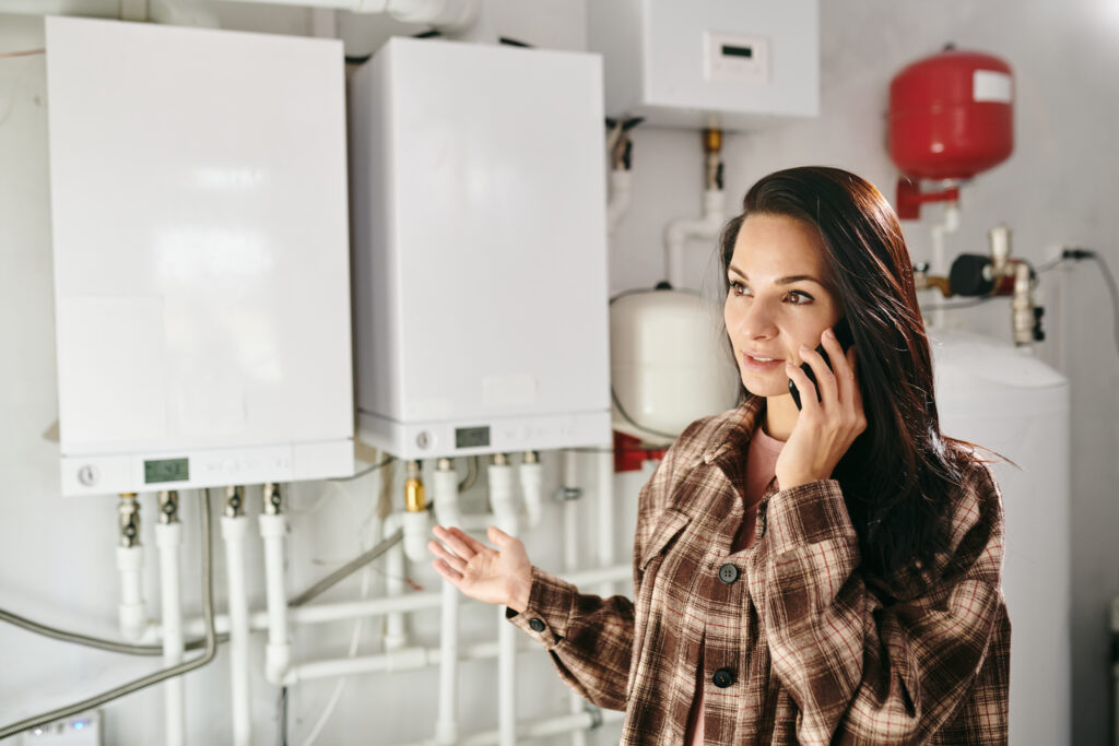 Young woman calling a plumber, representing the first step in finding out how much does it cost to replace a hot water system.